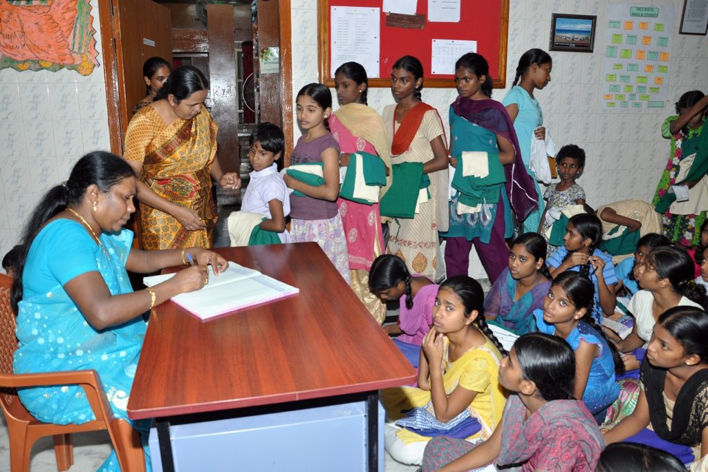 Children being handed out uniforms at the beginning of the academic year.